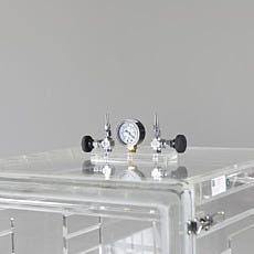 Pressure gauge and metering valves installed on clear Plexiglass vacuum chamber with front swing door