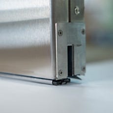 Close-up of stainless steel sliding door bottom seal and track hardware