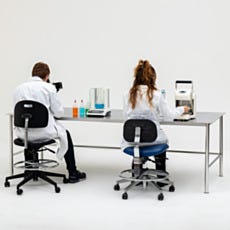 two scientists sitting at biosafe workstation using tools