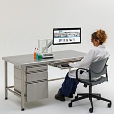 scientist sitting on chair typing on keyboard resting on keyboard tray attached to worksation
