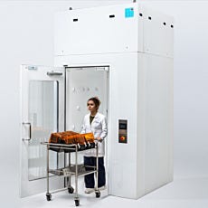 Lab technician exiting the cleanroom air shower while pushing a cart