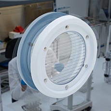 Clear round communication panel with transparent diaphragms mounted on a lab wall