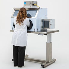 Lab technician operating a polypropylene glovebox on top of an adjustable-height table