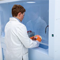 Over the shoulder view of a model using a spray gun inside the enclosed ValuLine® wet bench