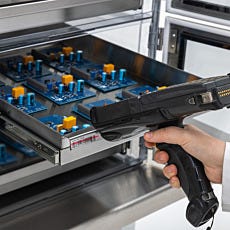 hand scanning a bardcode, on a stainless steel tray filled with microchips