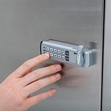 Hand entering code on digital combination lock keypad mounted on stainless steel cabinet door