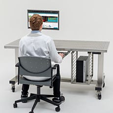 Lab technician working at cleanroom workstation with keyboard tray and monitor