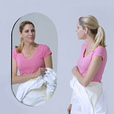 woman garbing in front of oval cleanroom mirror