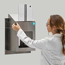 Lab technician activating a stainless steel pass-through with motorized raising and lowering doors