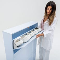 Close-up of lab technician placing cleanroom footwear into polypropylene shoe storage cabinet compartment