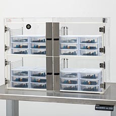 Stored electronic components in small desiccator drawers within an acrylic four-chamber desiccator