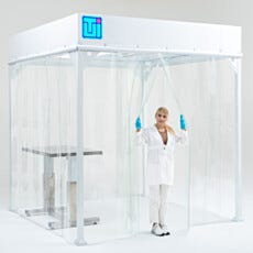 Lab technician entering softwall cleanroom through clear vinyl curtain door with hands-free access