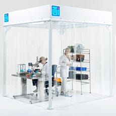 Two Lab Technicians in White Coats Working Inside Modular Softwall Cleanroom with Equipment