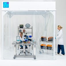 Two Laboratory Technicians Working Inside Softwall Cleanroom with Microscope Bench and Storage Cart