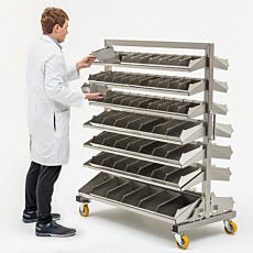 Photo of a man in a lab coat removing and replacing the bins of a stainless steel storage shelving unit