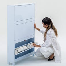 Lab technician accessing the bottom flip-down compartment of wall-mounted shoe storage cabinet