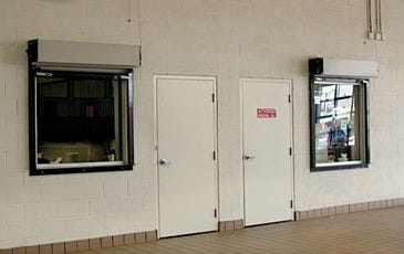 Two fire-rated roll-up doors on a wall with the slats rolled up