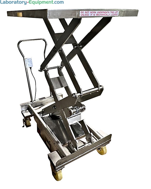 Stainless steel portable scissor lift table in raised position showing hydraulic mechanism, push handle, casters, and safety warning label on platform edg  |  1735-08 displayed